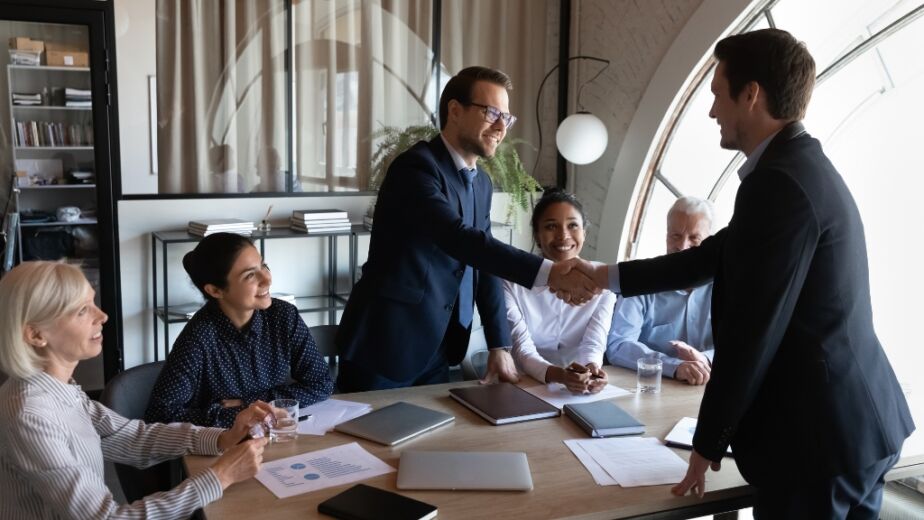 Man in contract role shaking hand of coworker in a friendly workplace culture