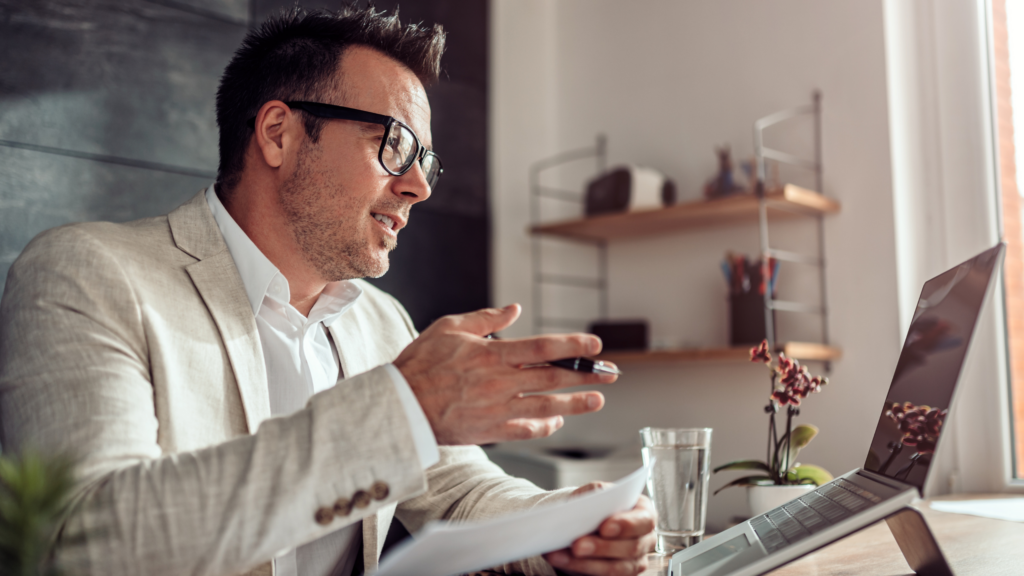 Remote recruiter holding pen while talking into laptop while hiring virtually